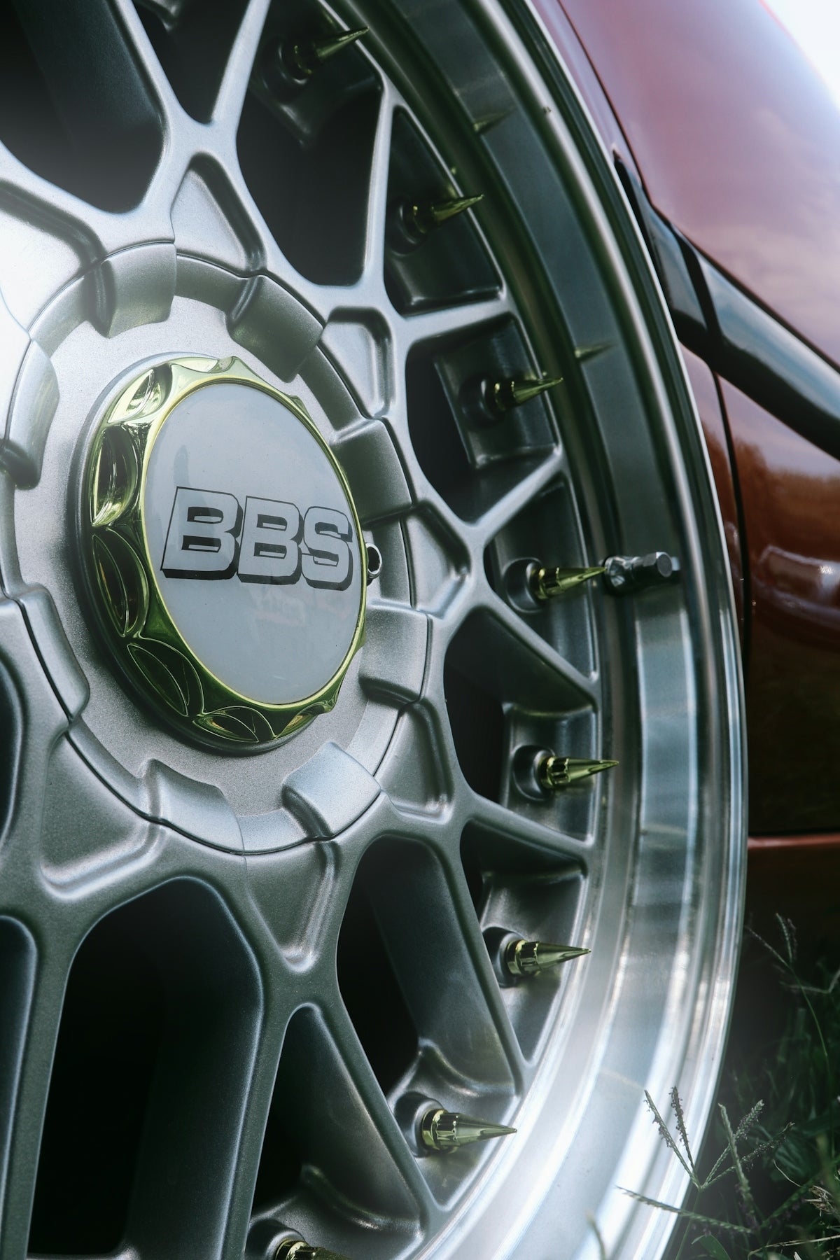 A silver bbs car wheel with gold spike lug nuts